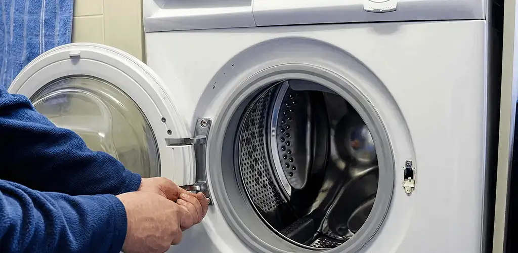 Washing machine repair handyman checking a front-load washer door and latch in Seattle, WA