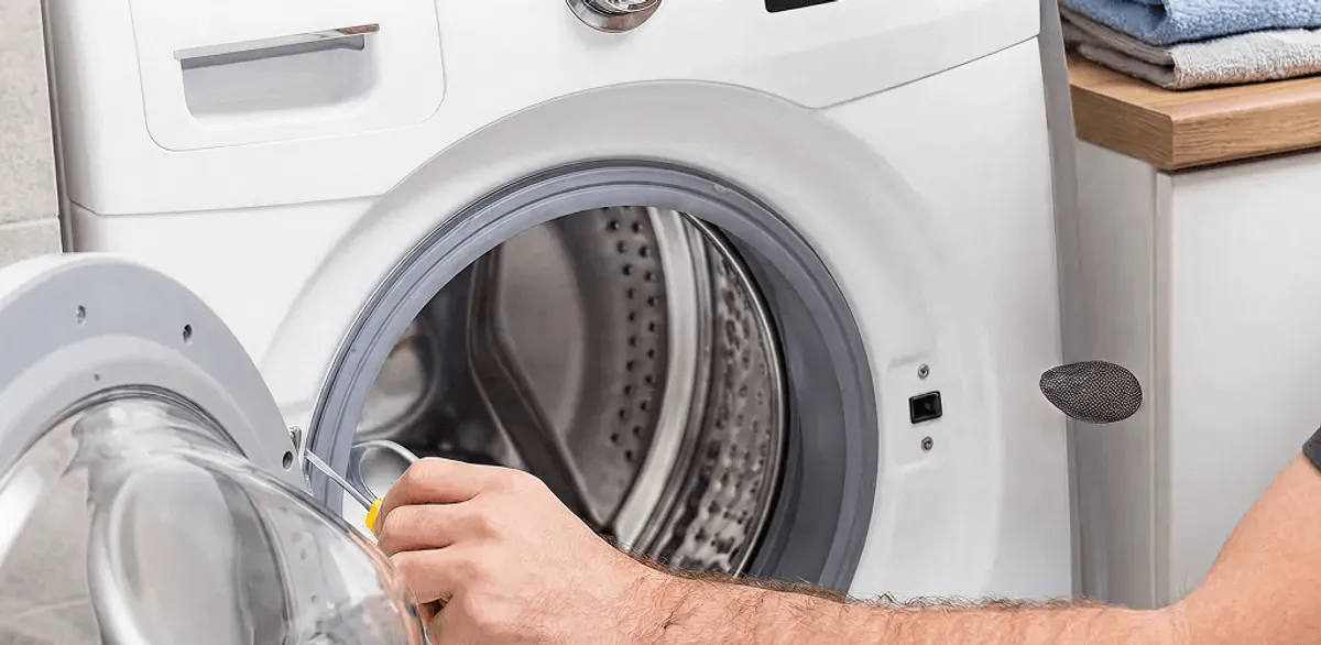 Handyman repairing a front-load washing machine and inspecting the drum in Seattle, WA