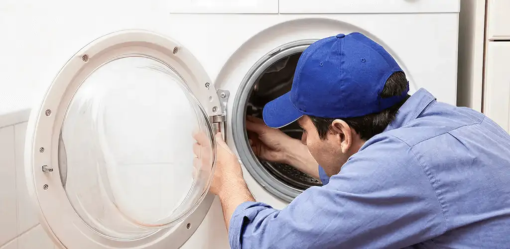 Washing machine repair handyman inspecting a front-load washer drum in Seattle, WA